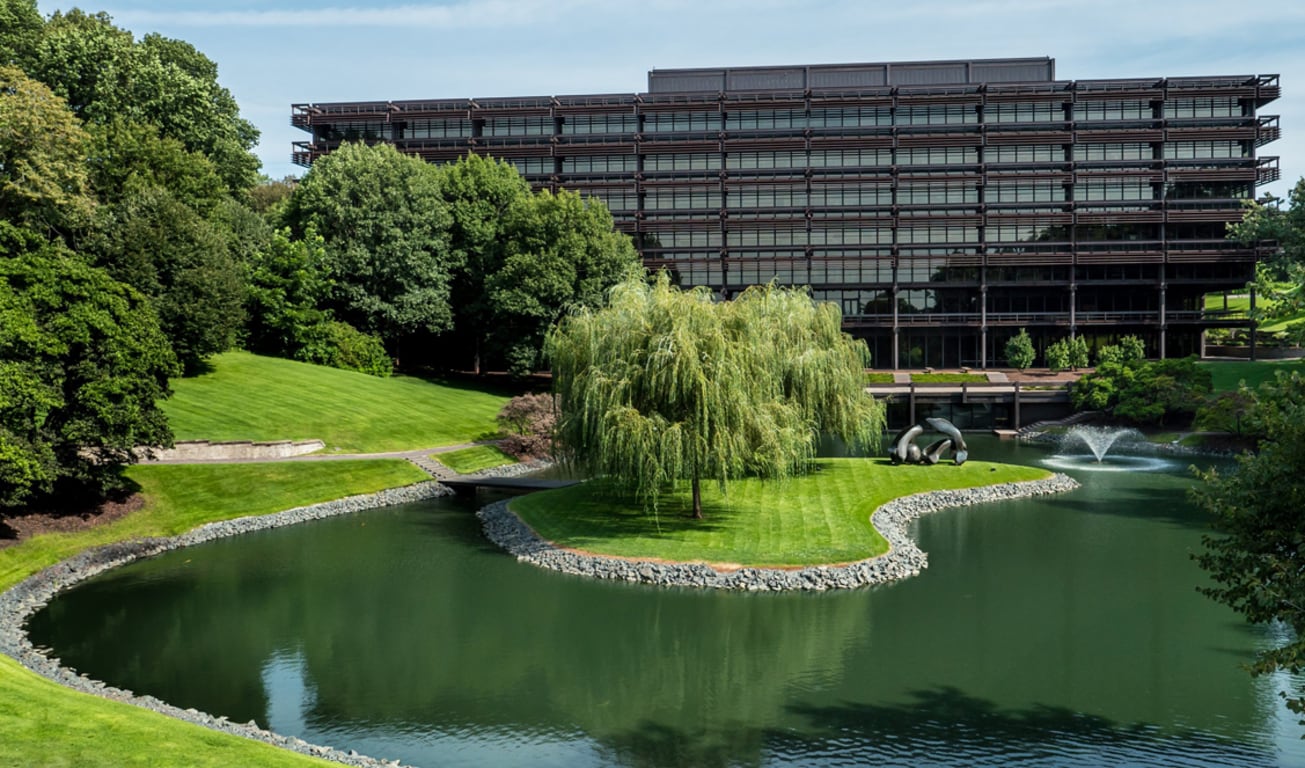 Weitläufige Frontaufnahme der John Deere Unternehmenszentrale mit einem Teich und Bäumen im Vordergrund