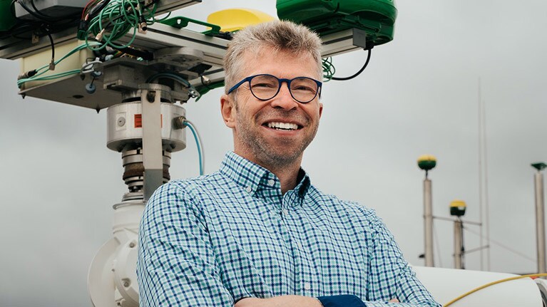 Georg Kormann, neben einem Roboterarm stehend.