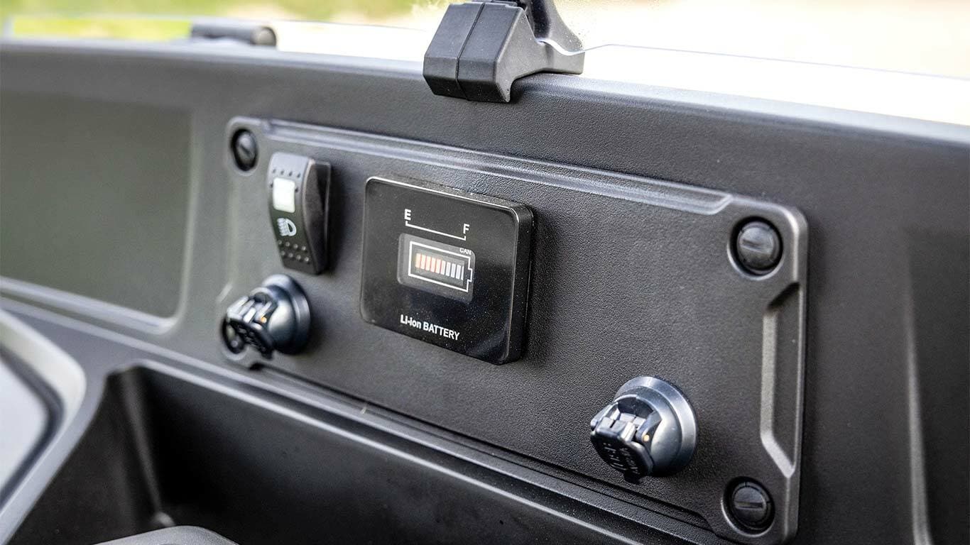 Armaturenbrett eines John Deere Gator GS Electric Modells mit Anzeige des Batteriestands und Stromanschlüssen.