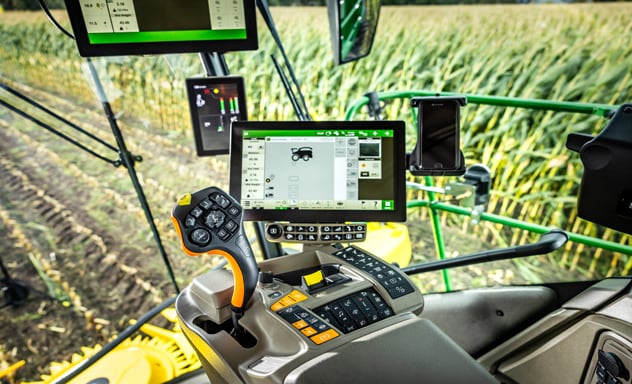 Selbstfahrender Feldhäcksler F9 700 beim Beladen eines Joskin Anhängers, der von einem John Deere Traktor 6R gezogen wird.