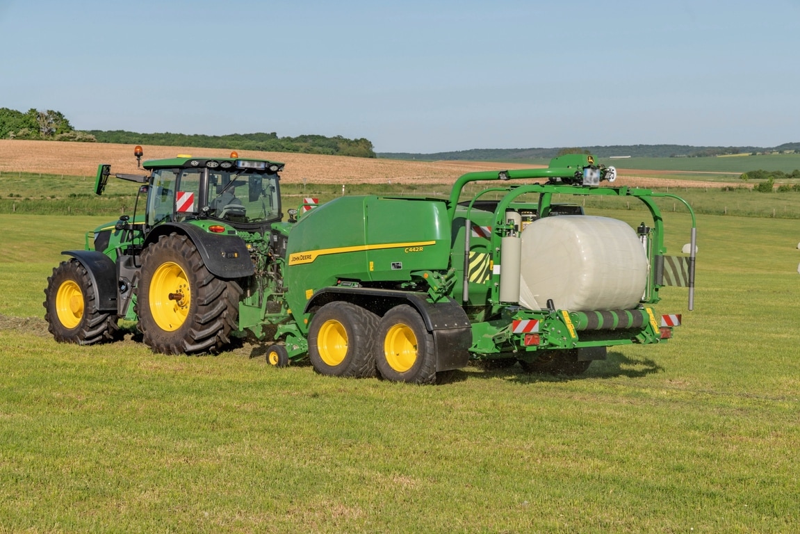 John Deere Kombipresse C442R, gezogen von einem John Deere 6R 185, zur Herstellung von Silageballen mit hoher Dichte.